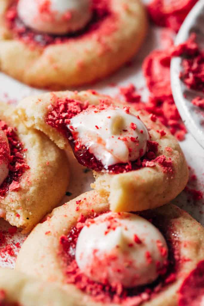 a bite taken out of a strawberry cookie topped with cheesecake