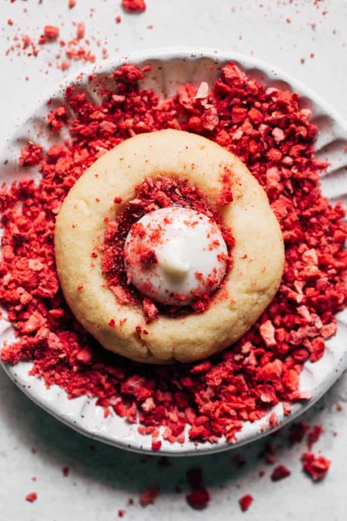 a strawberry cheesecake cookie on a plate of freeze dried strawberries