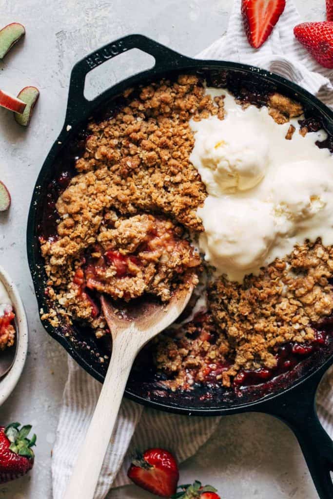 strawberry rhubarb crisp baked in a cast iron and topped with ice cream