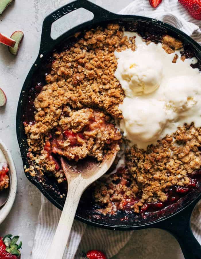strawberry rhubarb crisp baked in a cast iron and topped with ice cream