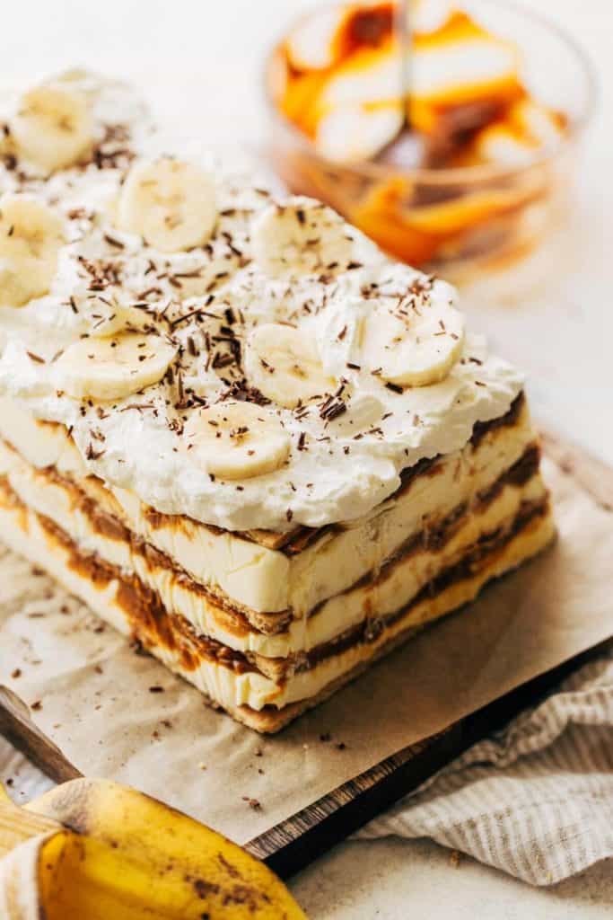 whipped cream and bananas on top of a layered banana icebox cake