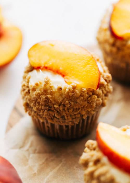 close up on a cupcake topped with a fresh peach slice