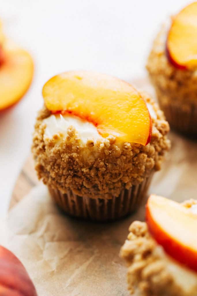 close up on a cupcake topped with a fresh peach slice