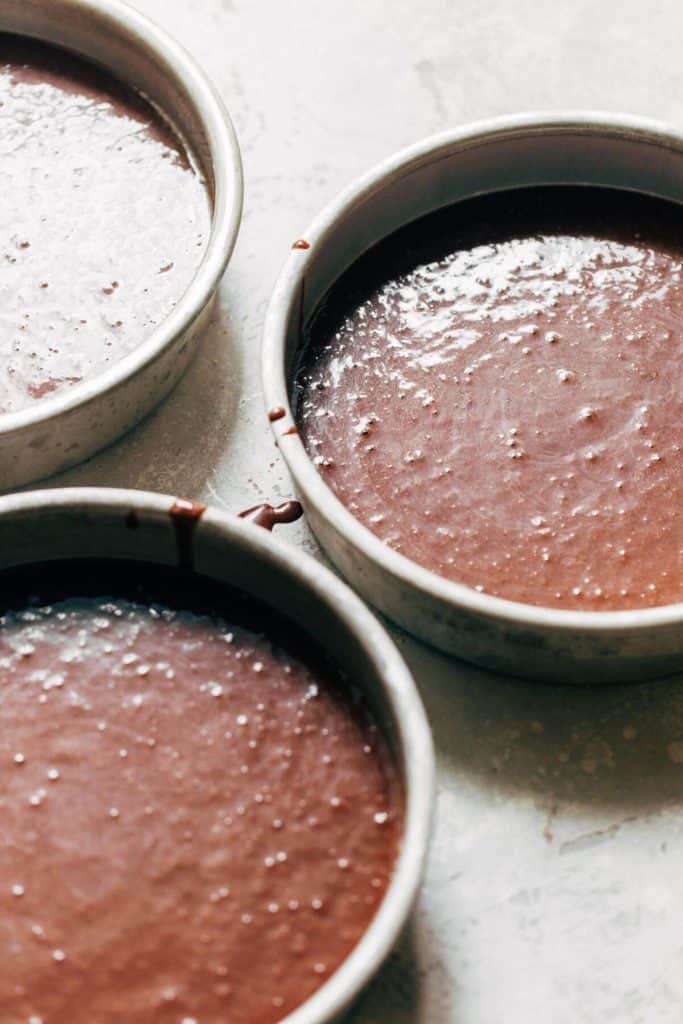 cake batter poured into three cake pans