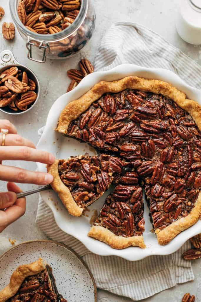 lifting a slice of pecan pie out of the pie dish