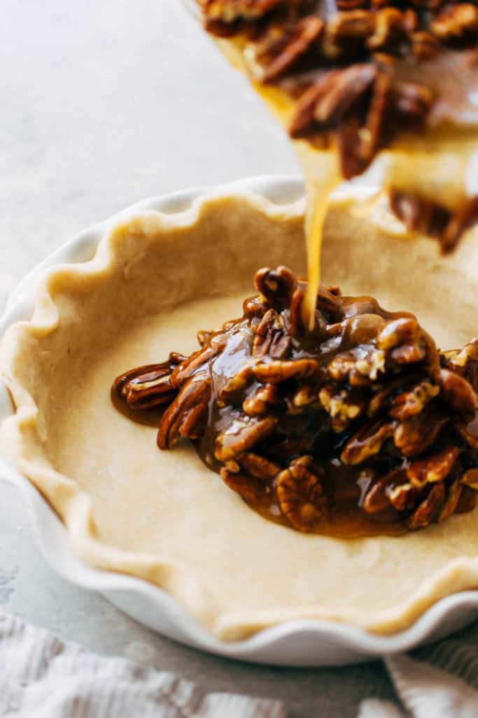 pouring pecan pie filling into a homemade pie shell