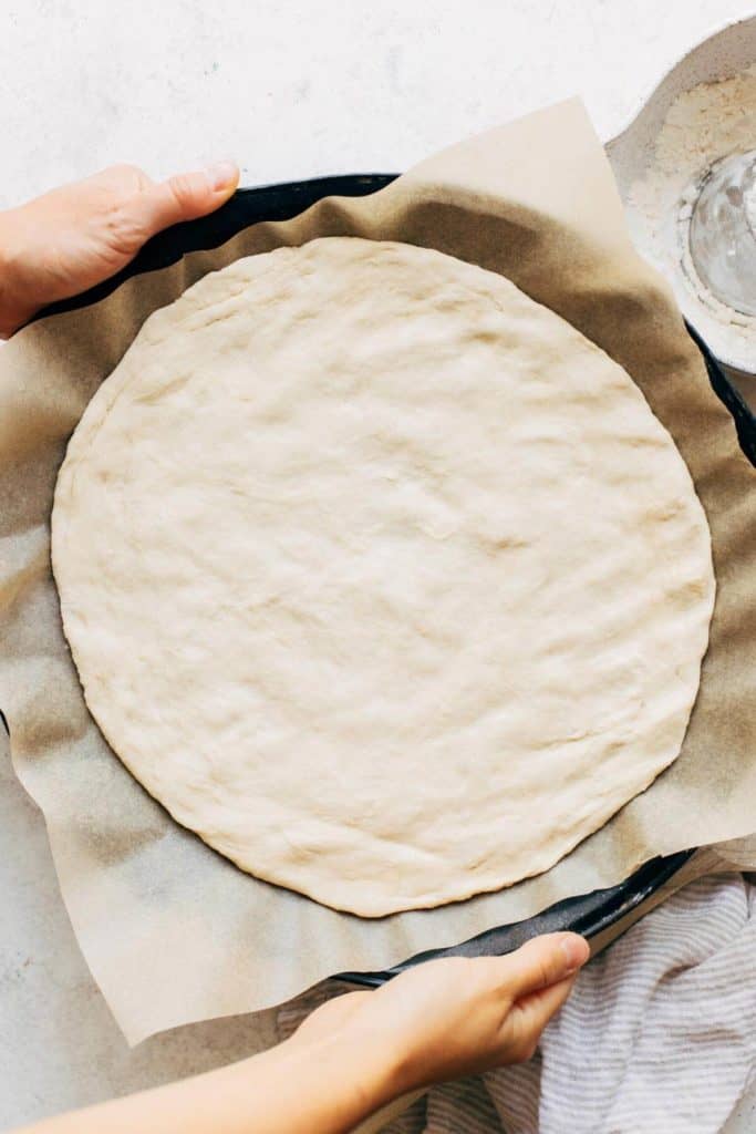 pizza dough pressed onto a pizza baking pan
