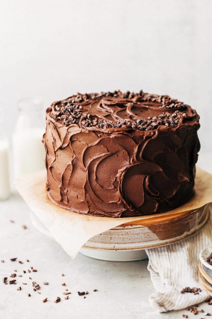 chocolate cake with swirled chocolate frosting sitting on a cake stand