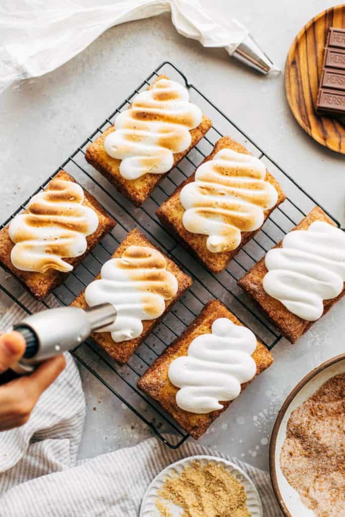 toasting marshmallow meringue swirled on top of smores puff pastries