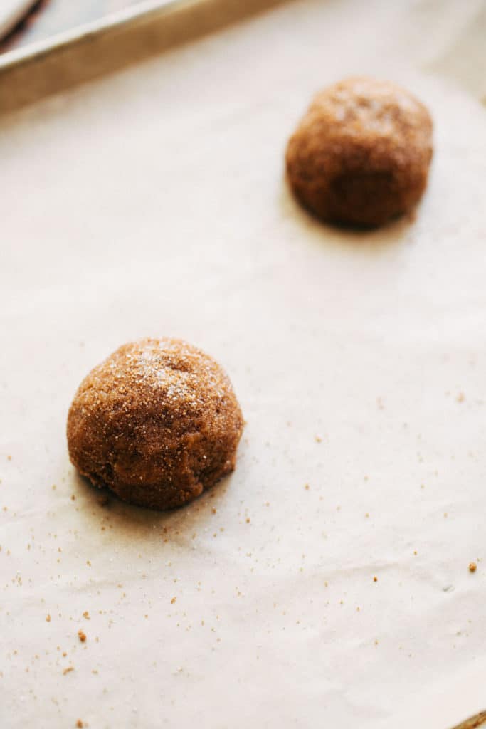 two cookie dough balls on a baking sheet