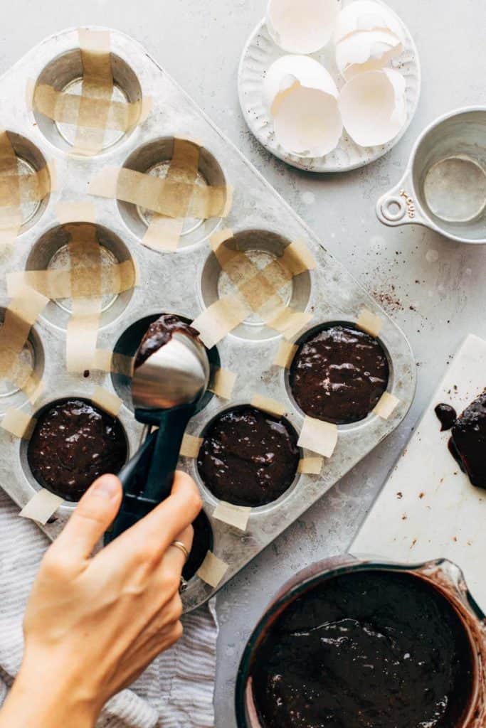 scooping brownie batter into a cupcake tin