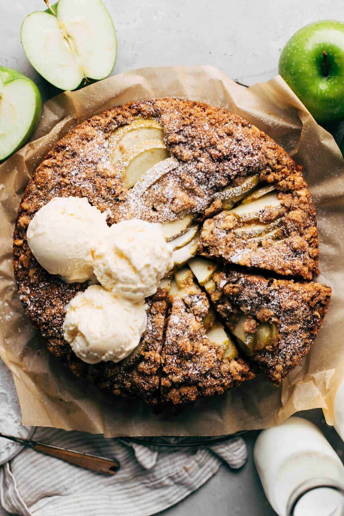 the top of an apple cake topped with scoops of ice cream