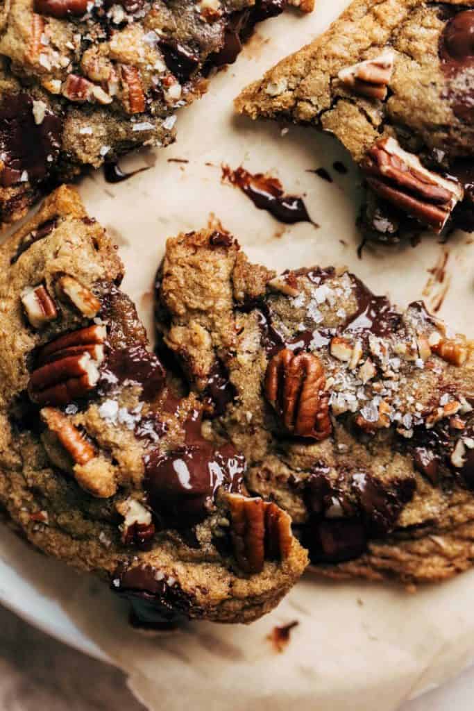 close up on a broken butter pecan cookie with smears of melted chocolate