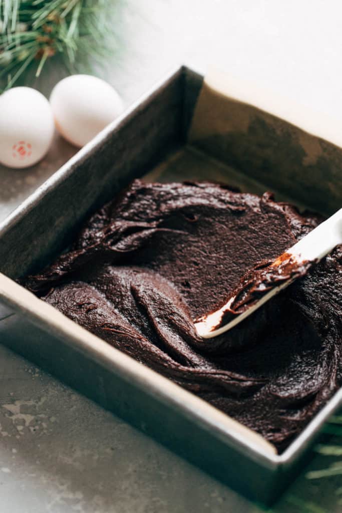 spreading brownie batter in a baking pan