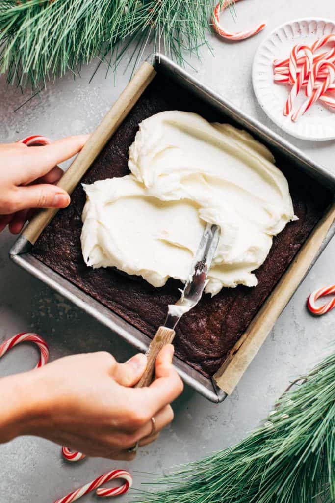 spreading peppermint buttercream on top of brownies