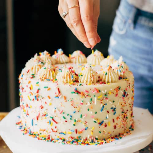 adding sprinkles to the top of a layer cake