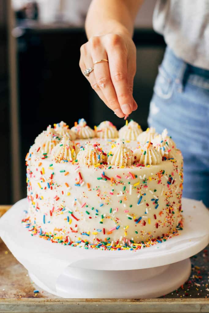 adding sprinkles to the top of a layer cake