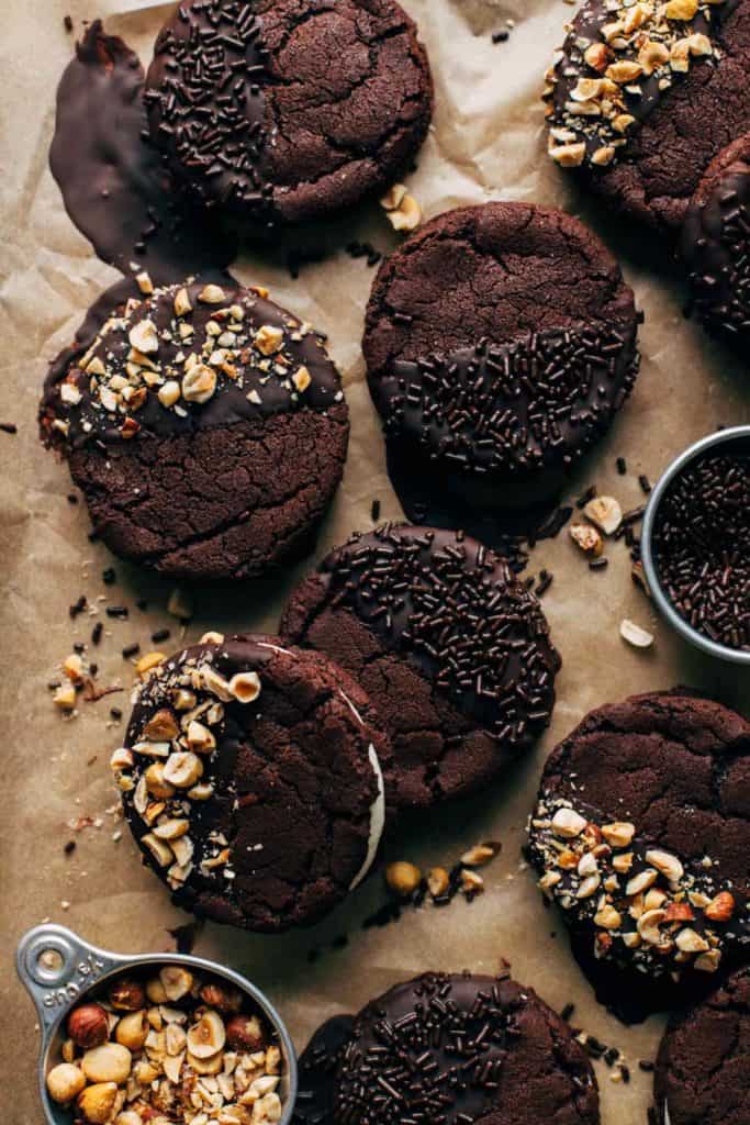 chocolate sandwich cookies half dunked in chocolate and scattered on parchment papper