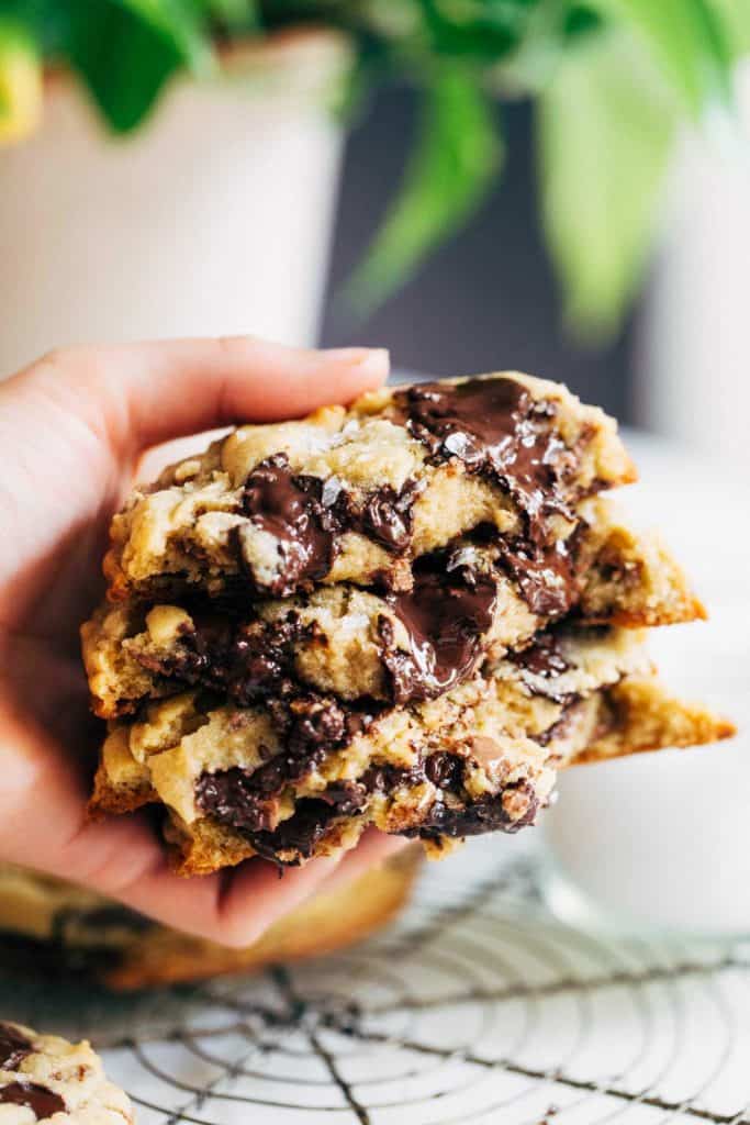 holding a stack of gooey bakery style chocolate chip cookies