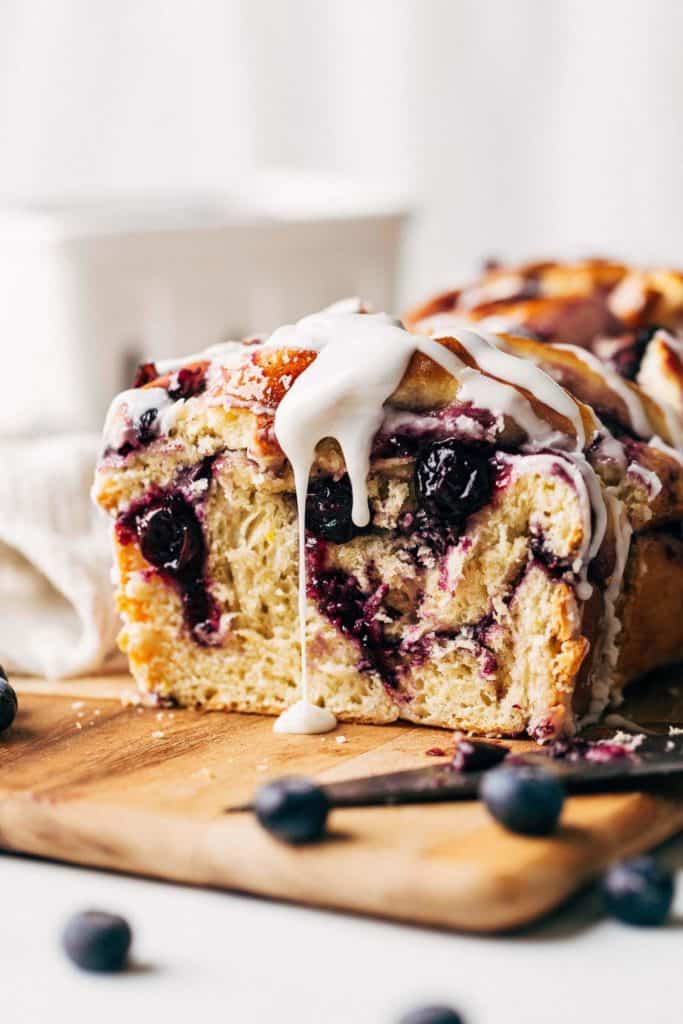 icing dripping down the side of a blueberry babka