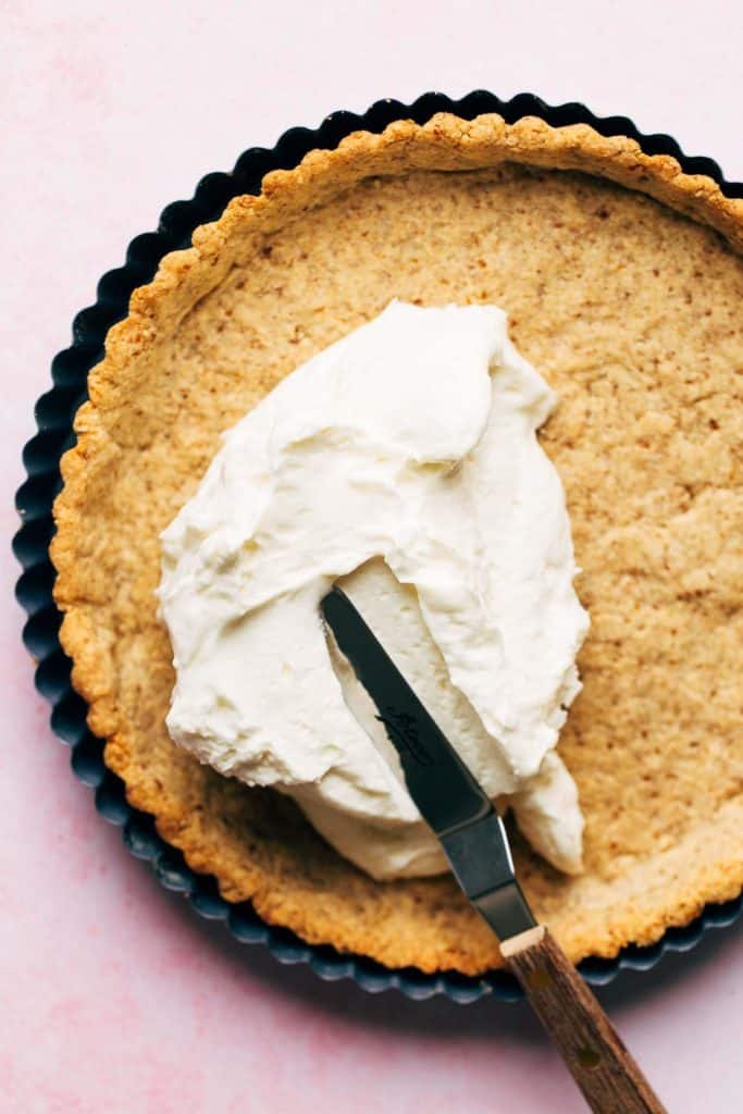 spreading cream cheese filling in a pretzel tart pie shell