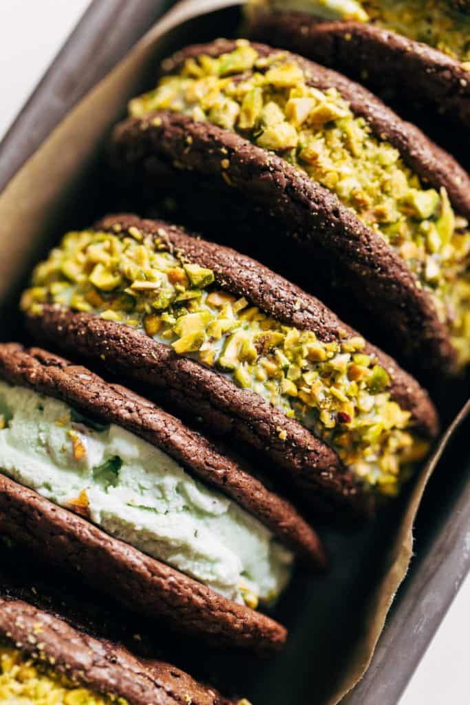 close up on the side of two brownie cookies sandwiched with pistachio ice cream