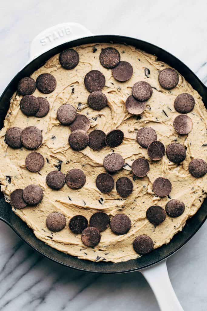 cookie dough spread in a skillet and topped with extra chocolate