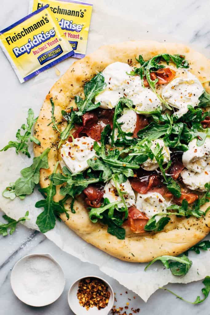 a prosciutto and burrata pizza topped with arugula