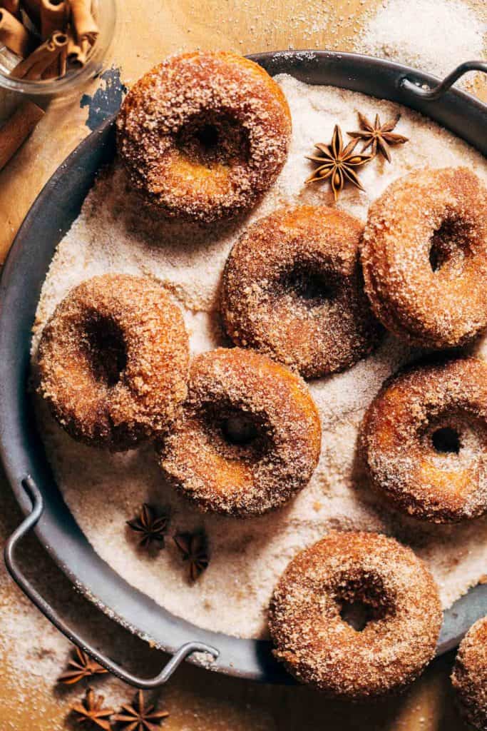 apple cider donuts scattered in a bed of cinnamon sugar