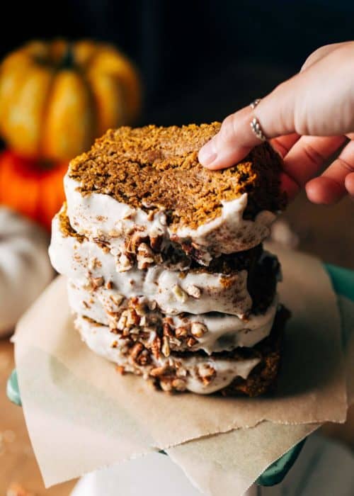 lifting a slice of pumpkin bread from a stack