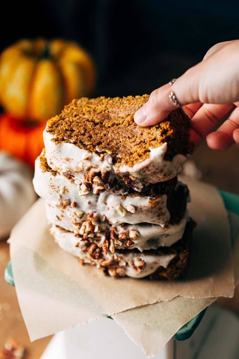 lifting a slice of pumpkin bread from a stack