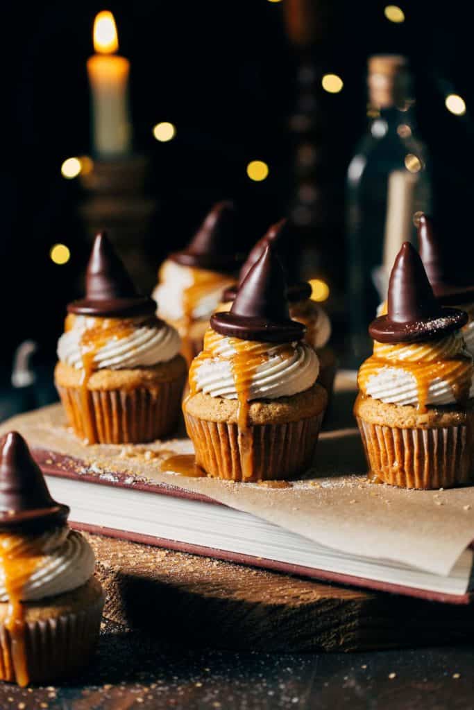 butterbeer cupcakes topped with butterscotch sauce and chocolate covered sorting hats