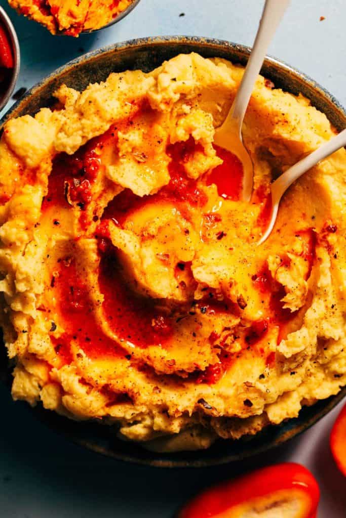 two spoons digging into a bowl of pimento butter mashed potatoes