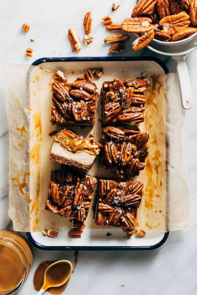 slices of caramel pecan cheesecake bars on a serving tray