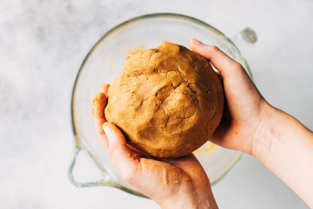 holding a ball of gingerbread cookie dough