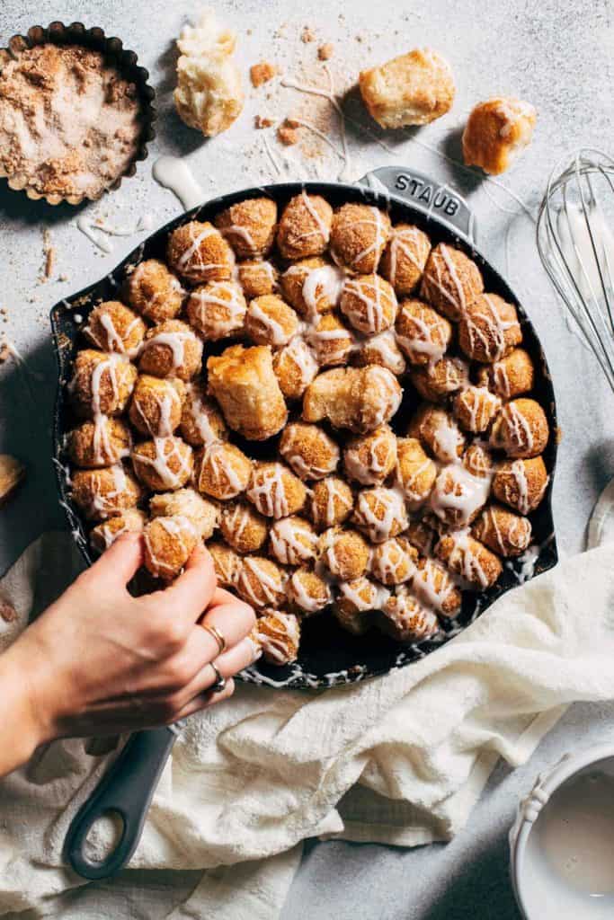 pulling pieces from monkey bread baked in a cast iron skillet