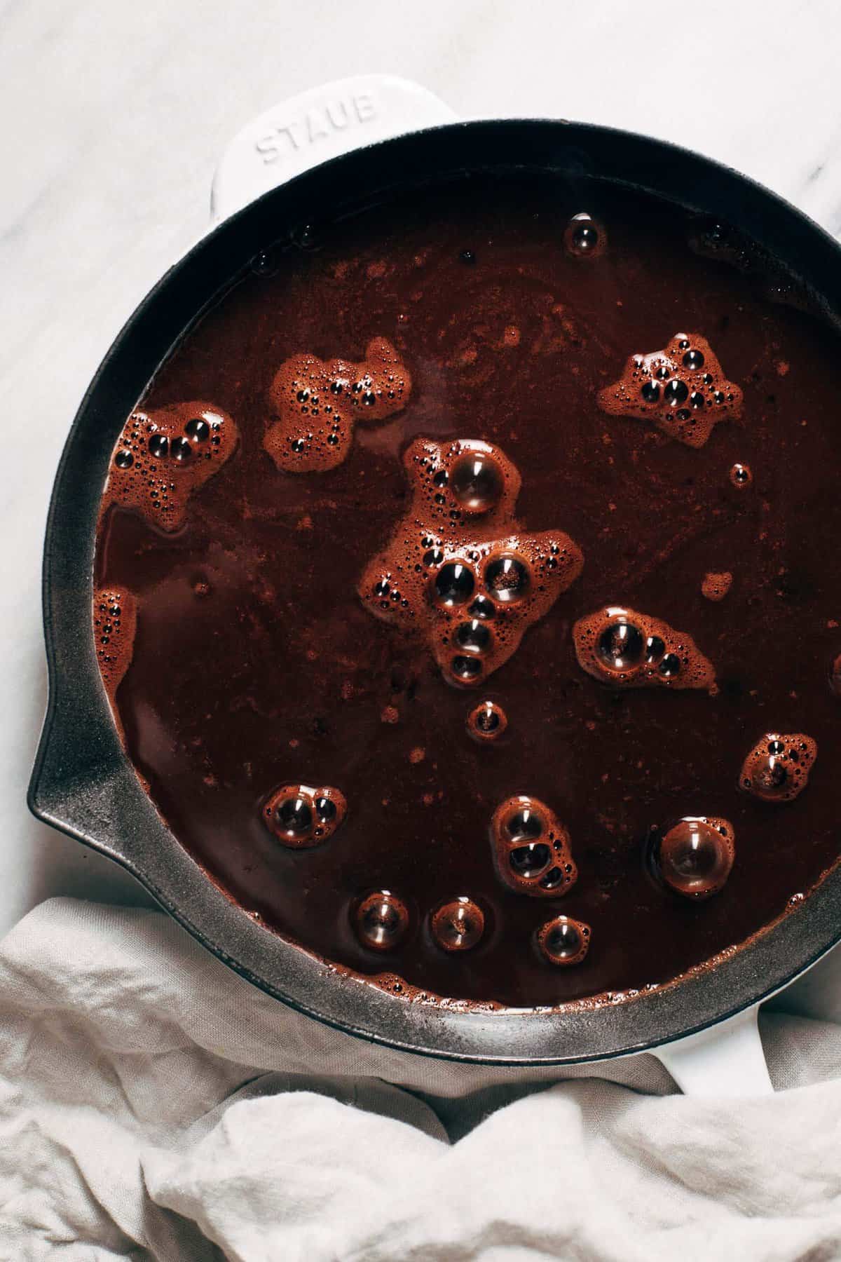 boiling water poured on top of chocolate cake batter in a skillet