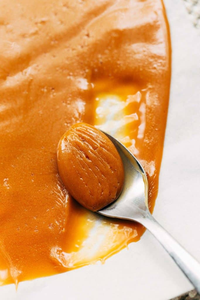 scraping caramel from a sheet of parchment paper