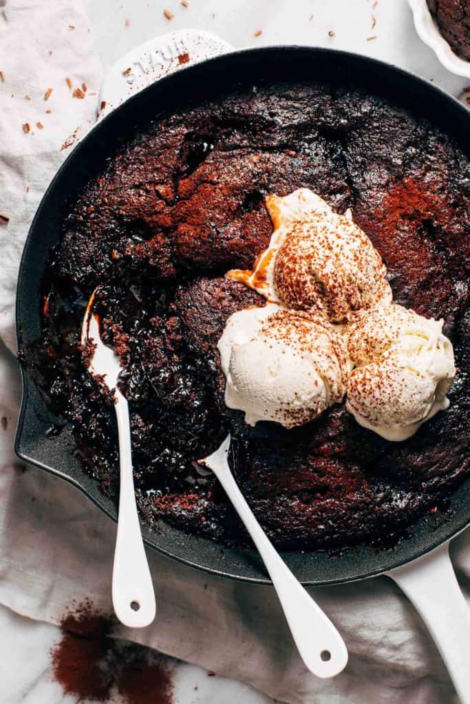 two spoons digging into a skillet of chocolate pudding cake