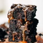 a stack of brownies with caramel dripping down the sides