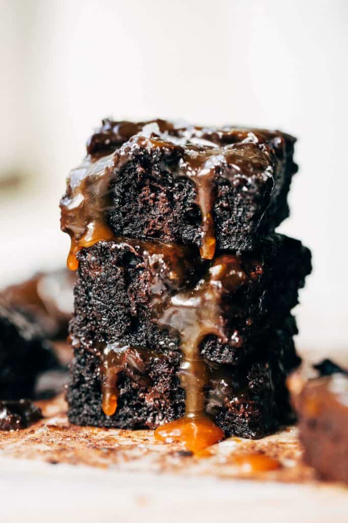 a stack of brownies with caramel dripping down the sides