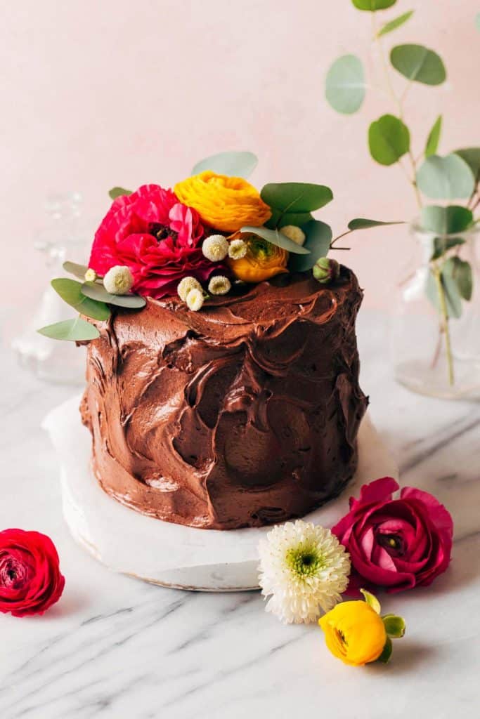 a chocolate cake covered in chocolate frosting and topped with flowers