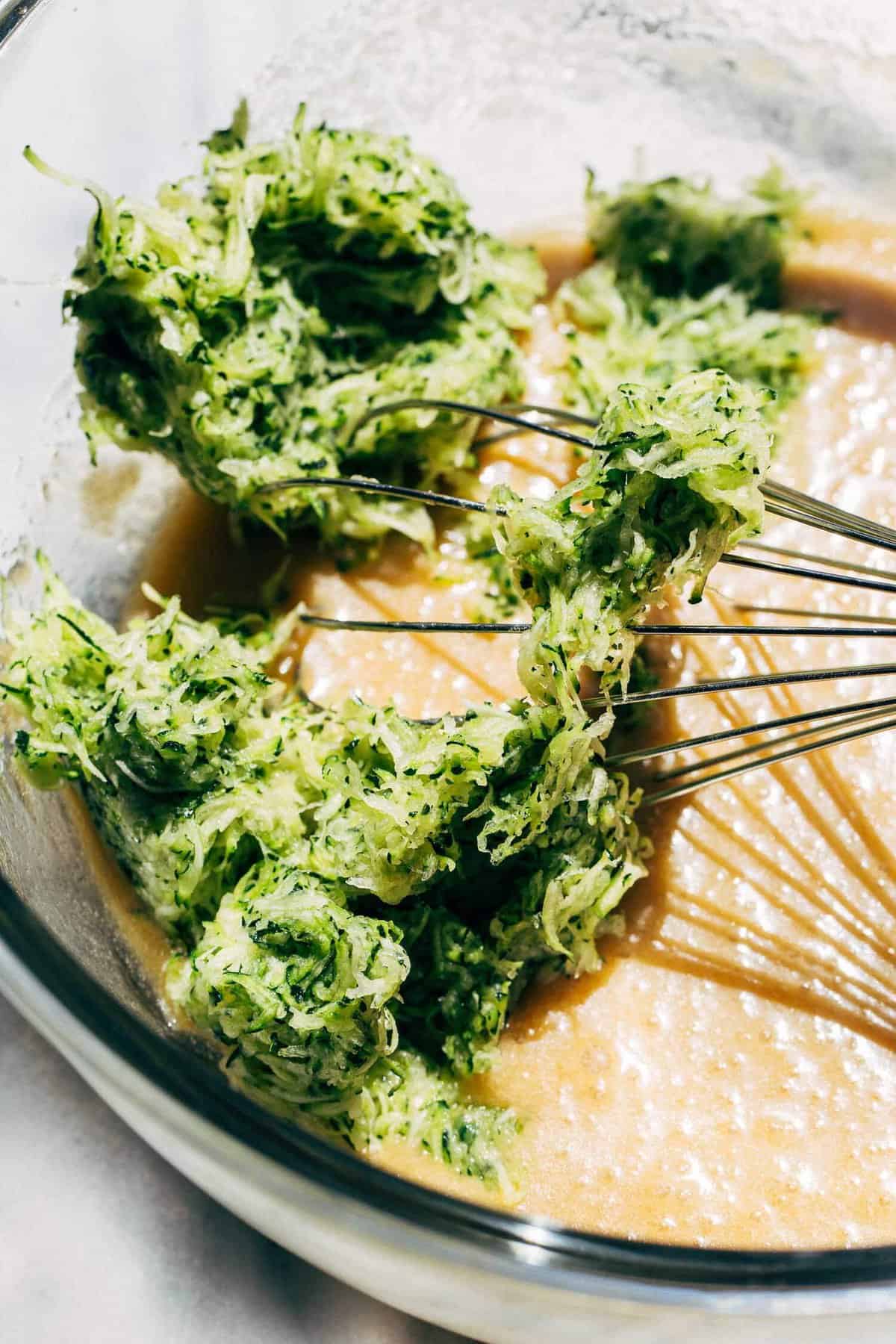 shredded zucchini in a bowl of zucchini bread batter