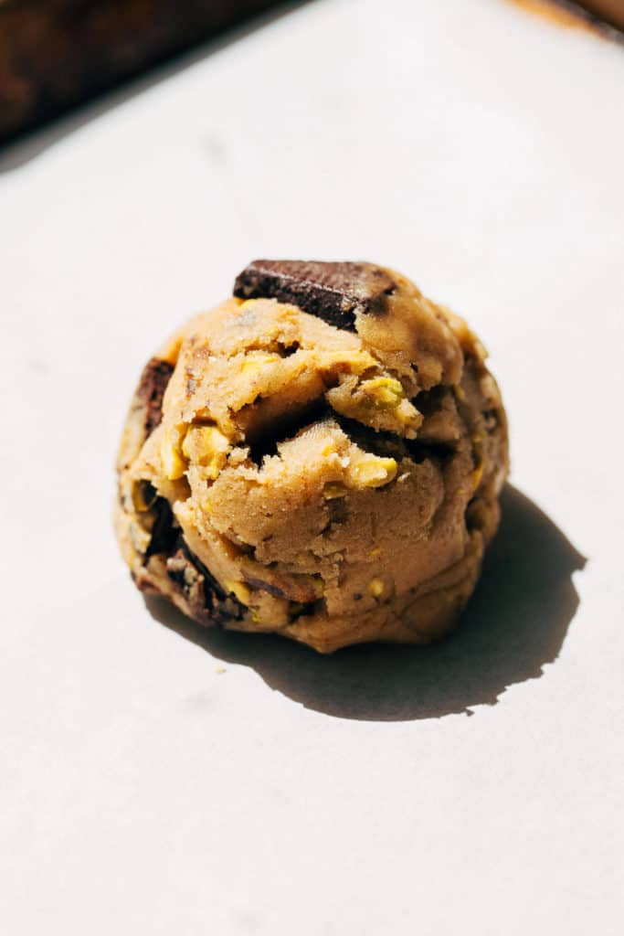 a bowl of scooped cookie dough on a baking sheet