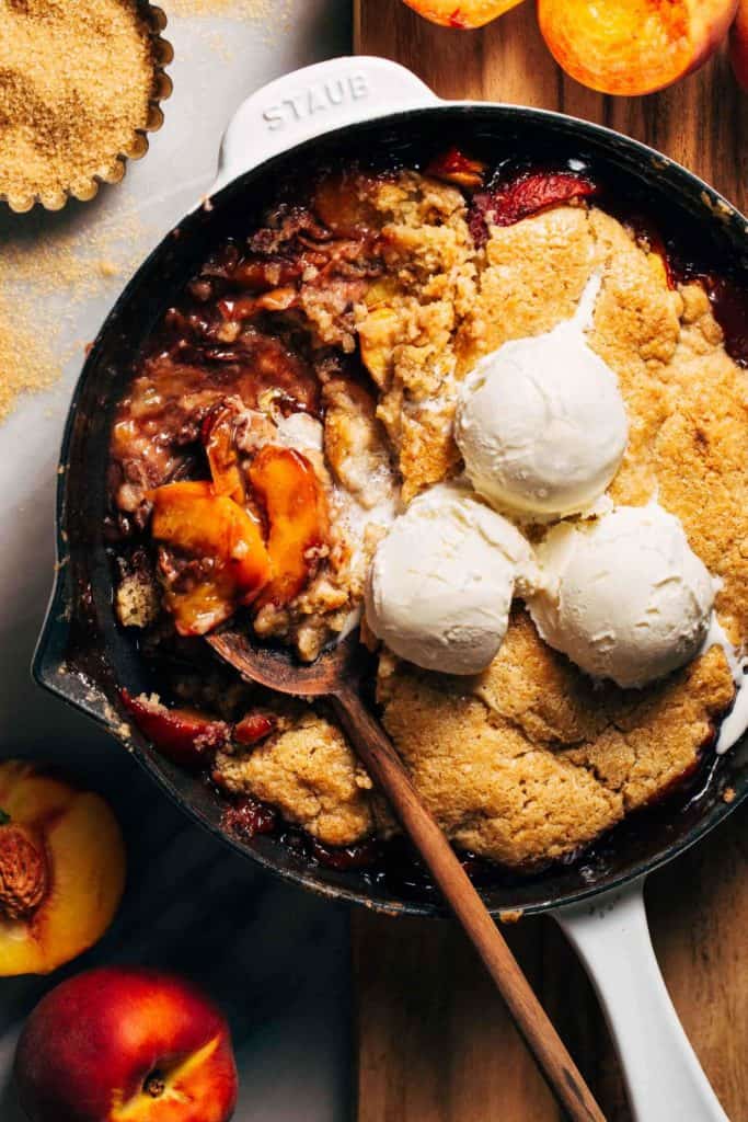 a spoon digging into skillet peach cobbler