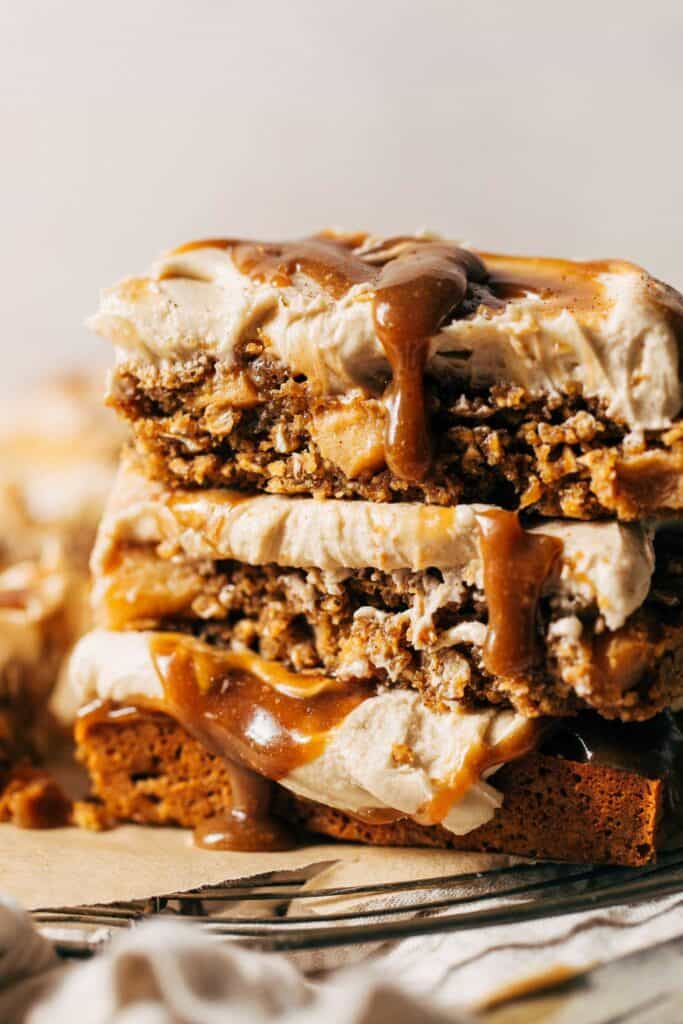 a stack of frosted apple blondies with caramel drizzling down the sides