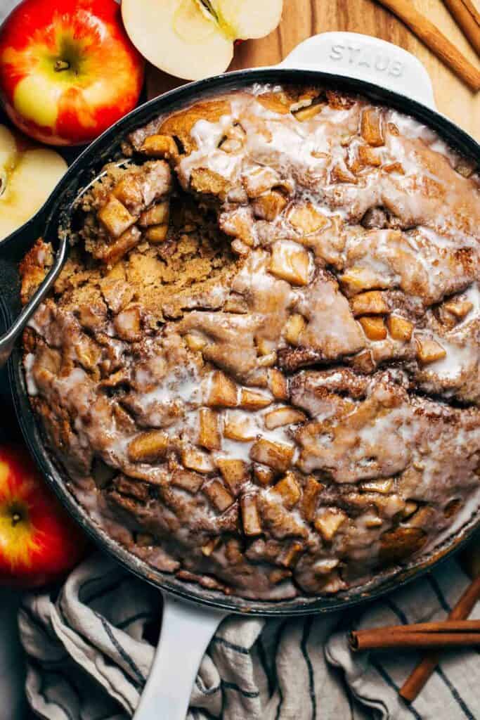 an apple fritter cake baked in a skillet with an icing glaze