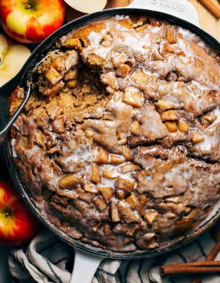 an apple fritter cake baked in a skillet with an icing glaze