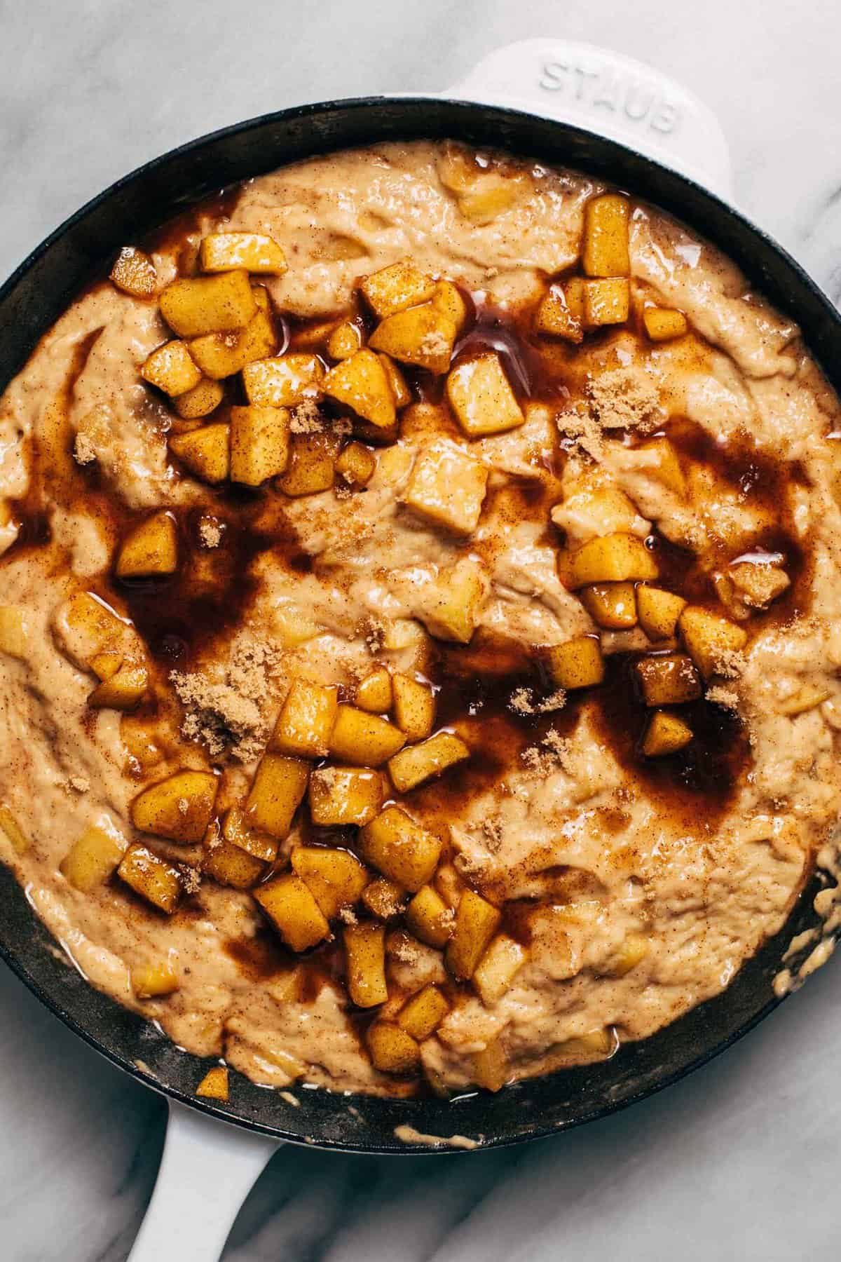 apple fritter cake batter in a skillet that's topped with tender spiced apples