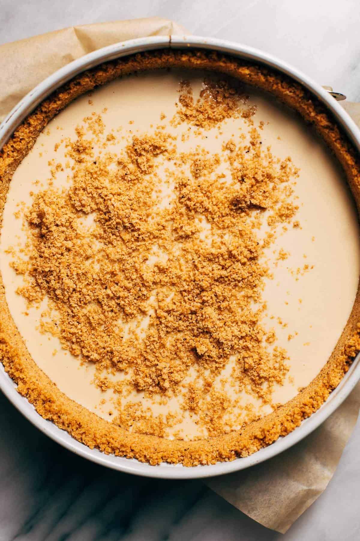 sprinkling graham cracker crust in the center of a cheesecake